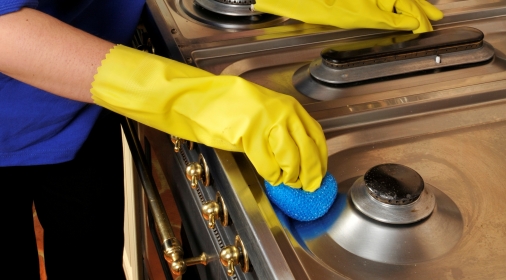 yellow rubber gloves cleaning an oven hob